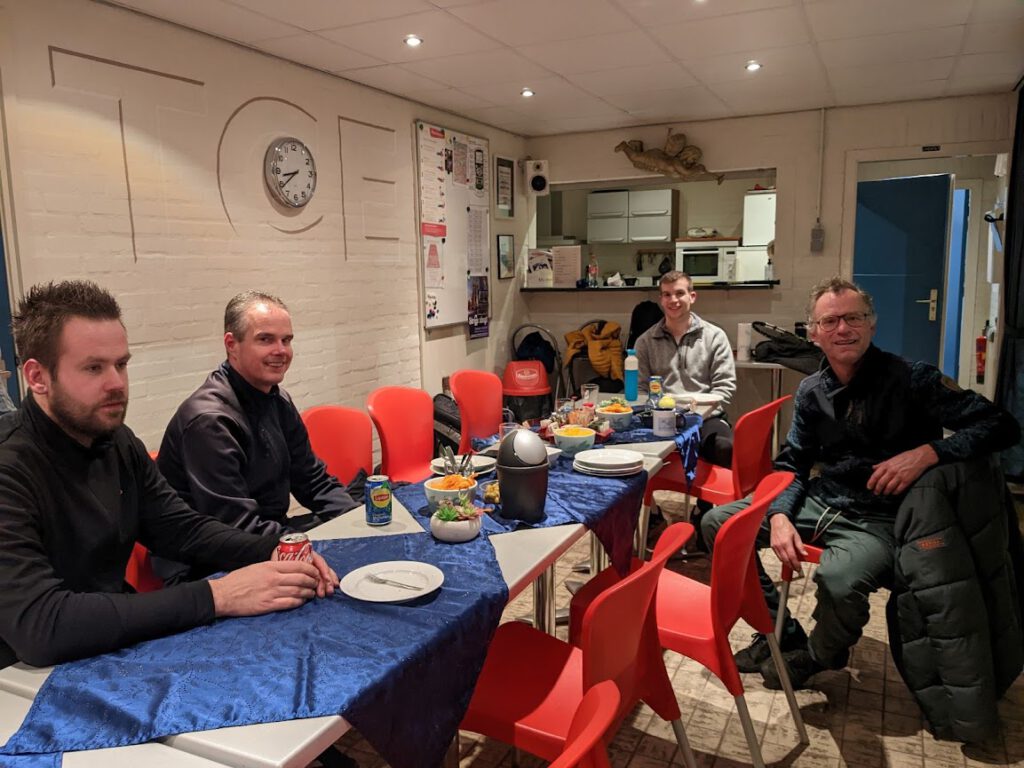 4 mannen genietend van eten en drinken na een KNLTB tenniswedstrijd