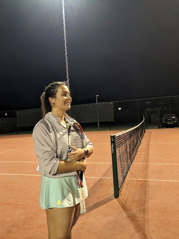Een meisje dat met haar tennisracket op de tennisbaan staat